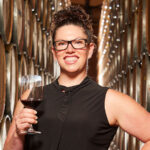 Winemaker with a glass of red wine in a barrel room